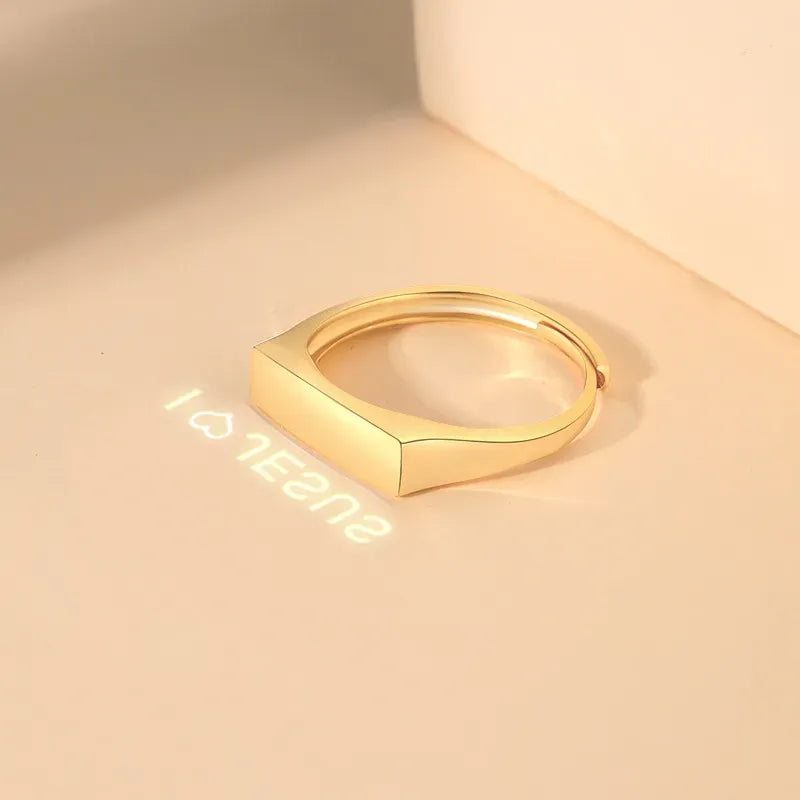 The Secret Light Projection Ring gold band on a soft background